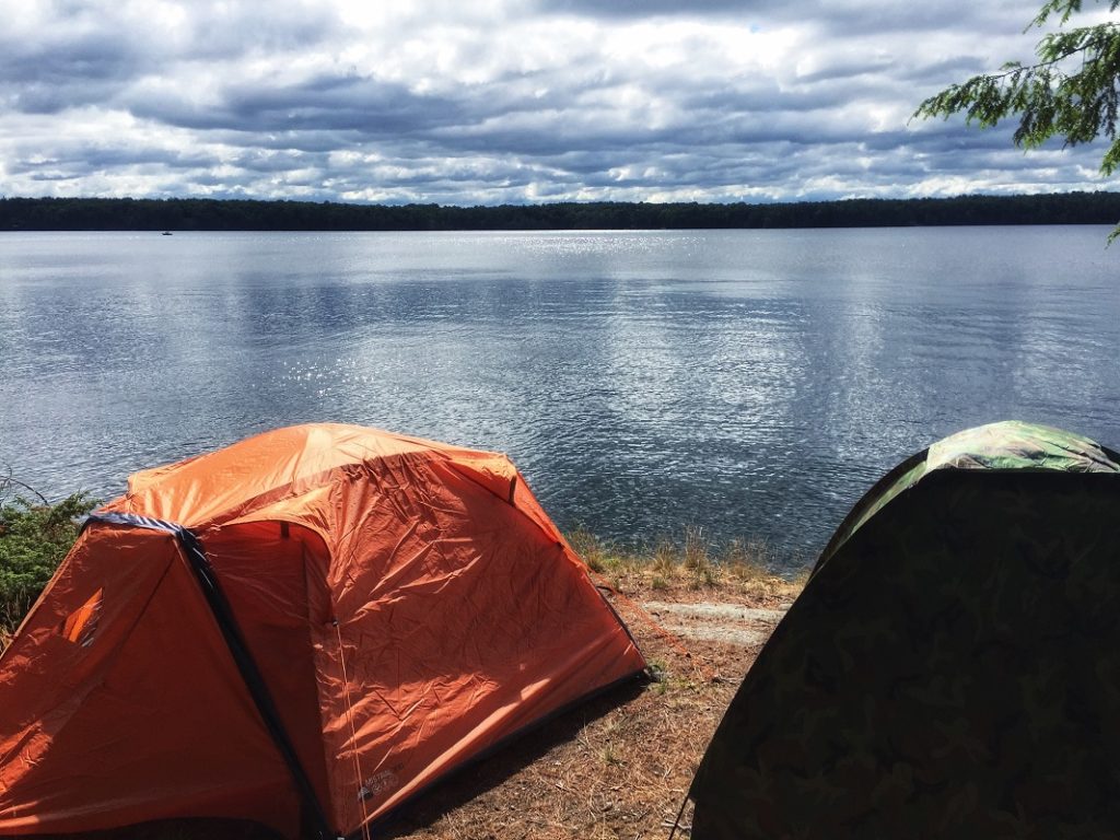 two tents right by the lake - camping next to a lake