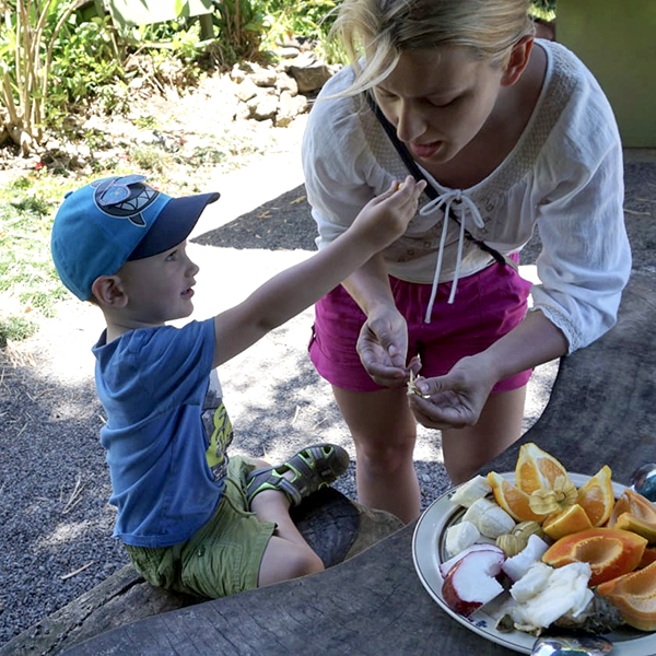 child feeding his mom with exotic fruit