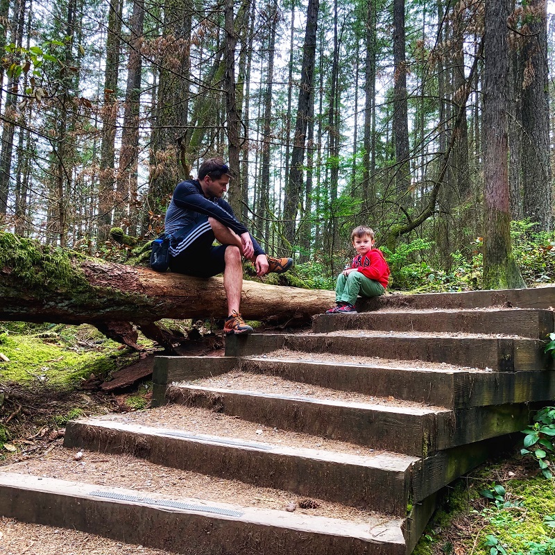 a father and child resting sitting on wooden steps in the forest