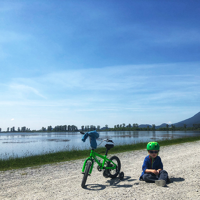 a child sitting near a bike at Rannie Road in Pitt Lake Ecological Reserve, near Pitt Meadows, BC Grant Narrows Regional Park