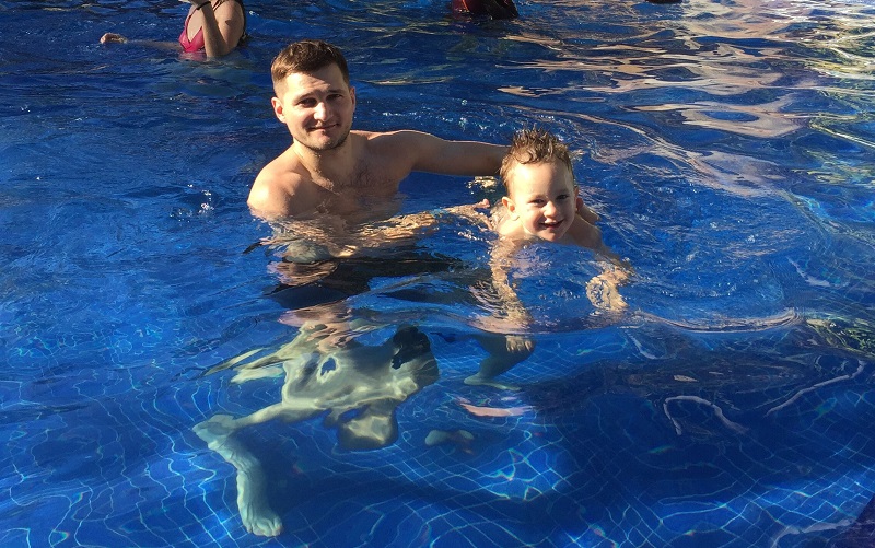 father and son swimming in a pool on a summer vacation