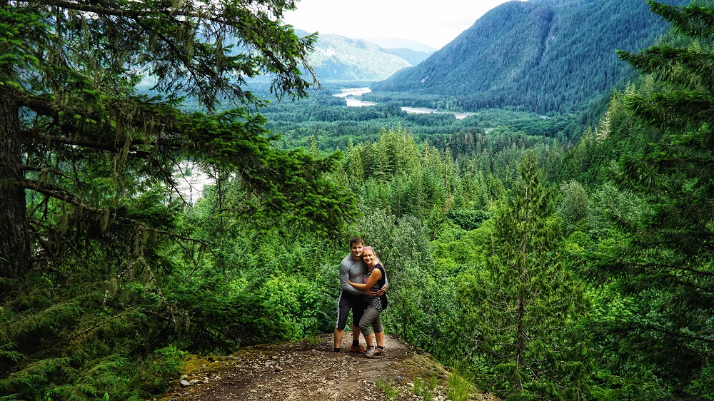 couple hugging at a viewpoint of the Squamish Valley from a hiking trail