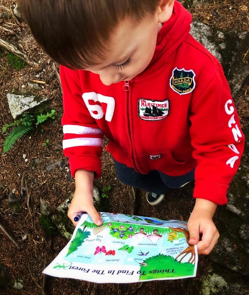 toddler holding outdoor treasure hunt activity at a hike