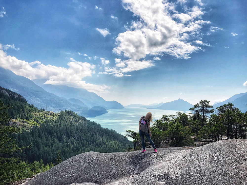 Blonde girl and the backdrop of Howe Sound as seen from Jurassic Ridge hiking trail in Murrin Provincial Park BC Canada next to Squamish
