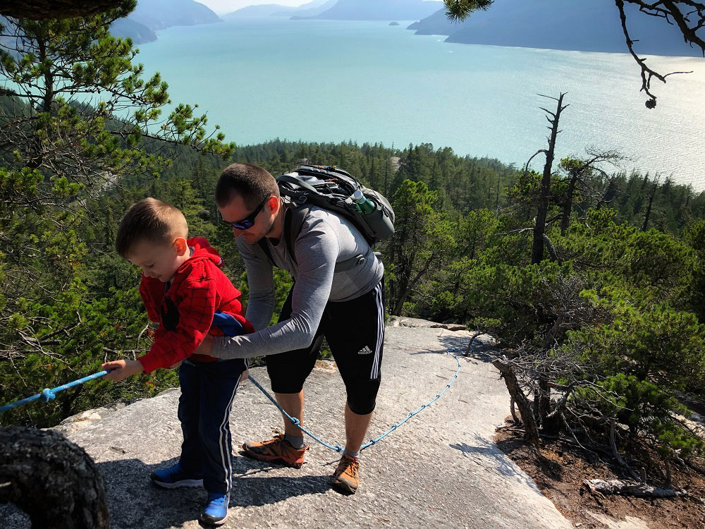 Father and son rope climbing the Jurassic Ridge hiking trail rope in Murrin Provincial Park near Squamish in BC Canada