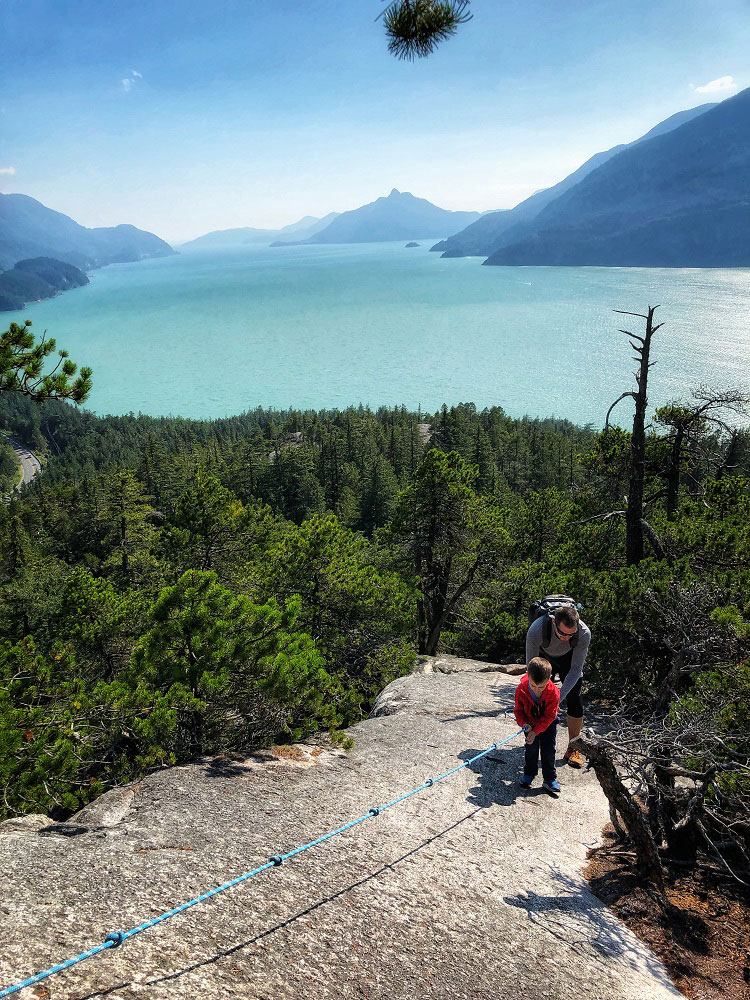Father and son descending the rope at the Jurassic Ridge hiking trail rope in Murrin Provincial Park near Squamish in BC Canada
