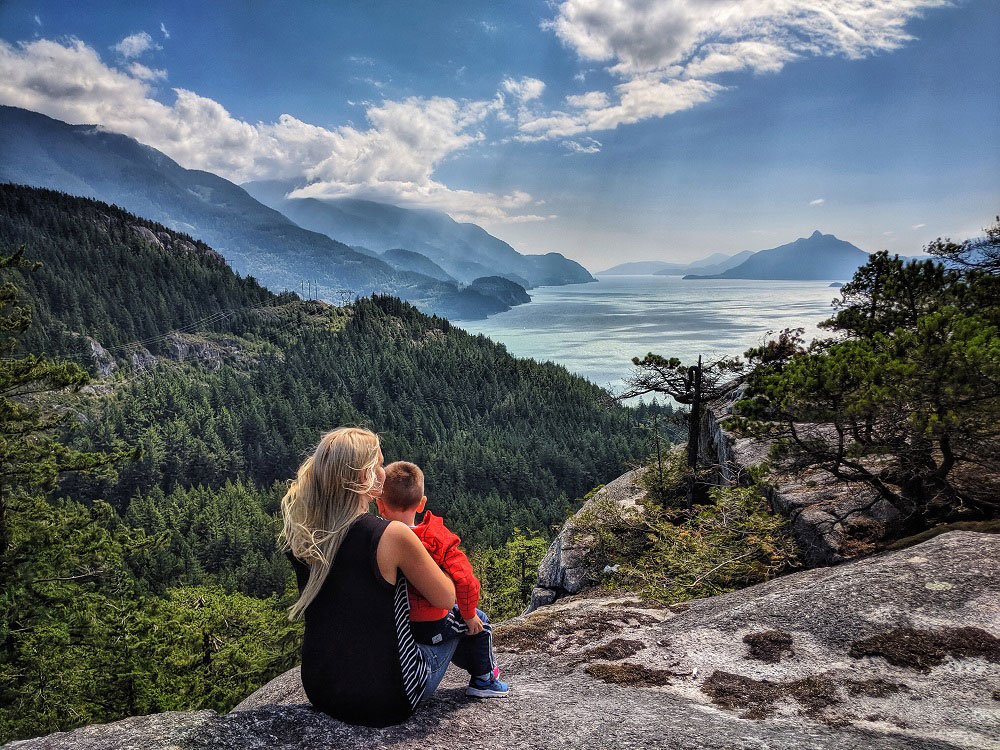 Mother hugging her child while they view Howe Sound from Jurassic Ridge hiking trail in Murrin Provincial Park near Squamish in BC Canada