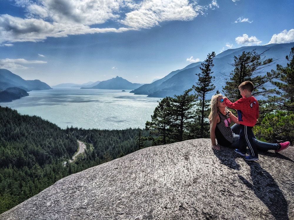 mom and son playing on a kids-friendly hike with view Howe Sound from Jurassic Ridge hiking trail in Murrin Provincial Park near Squamish in BC Canada