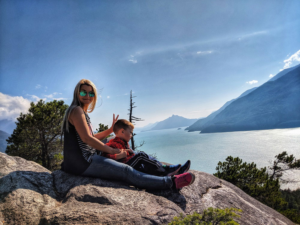 mother and son relaxing summer evening on top of the Jurassic Ridge trail with the view of Howe Sound at sunset - BC Canada