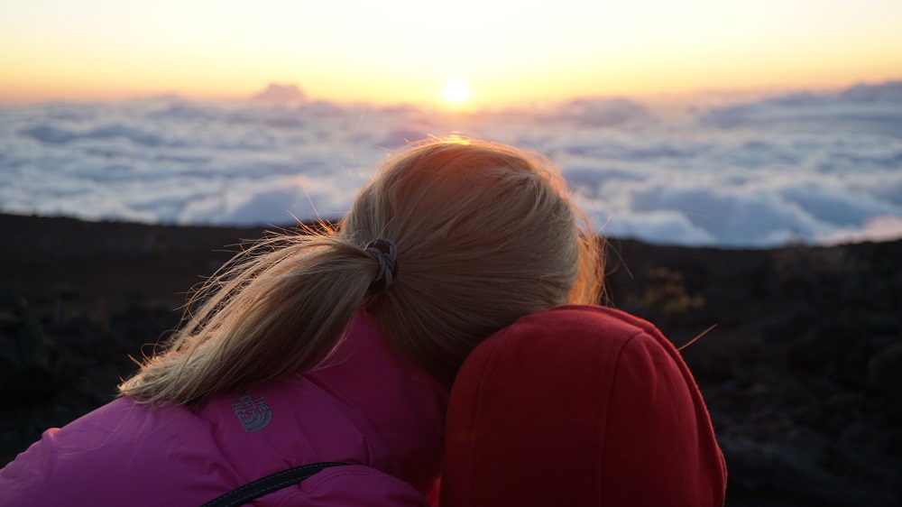 Mother and child watching sunrise at Haleakala Volcano summit in Maui Hawaii