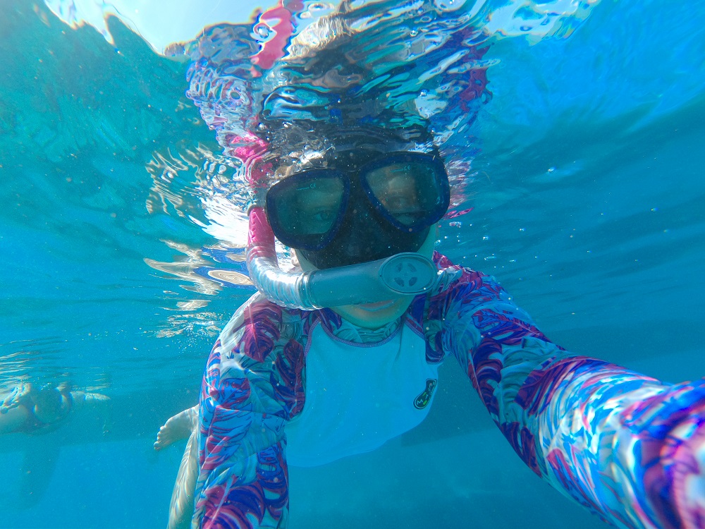 Woman in a snorkel taking a selfie under water