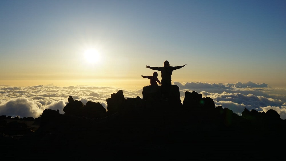 Mother and son silhouettes above clouds - sunset at Haleakala Volcano - Maui - a drone to be added to packing list 