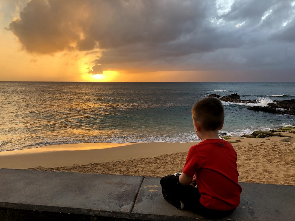 Child watching a golden sunset at Kahana Sunset vacation rentals in Maui Hawaii