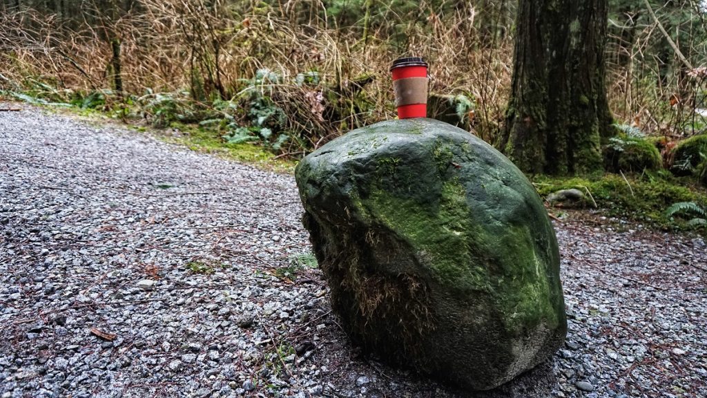 single use coffee cup a top of a boulder - waste disposal. Pack it in pack it out outdoor ethics principle