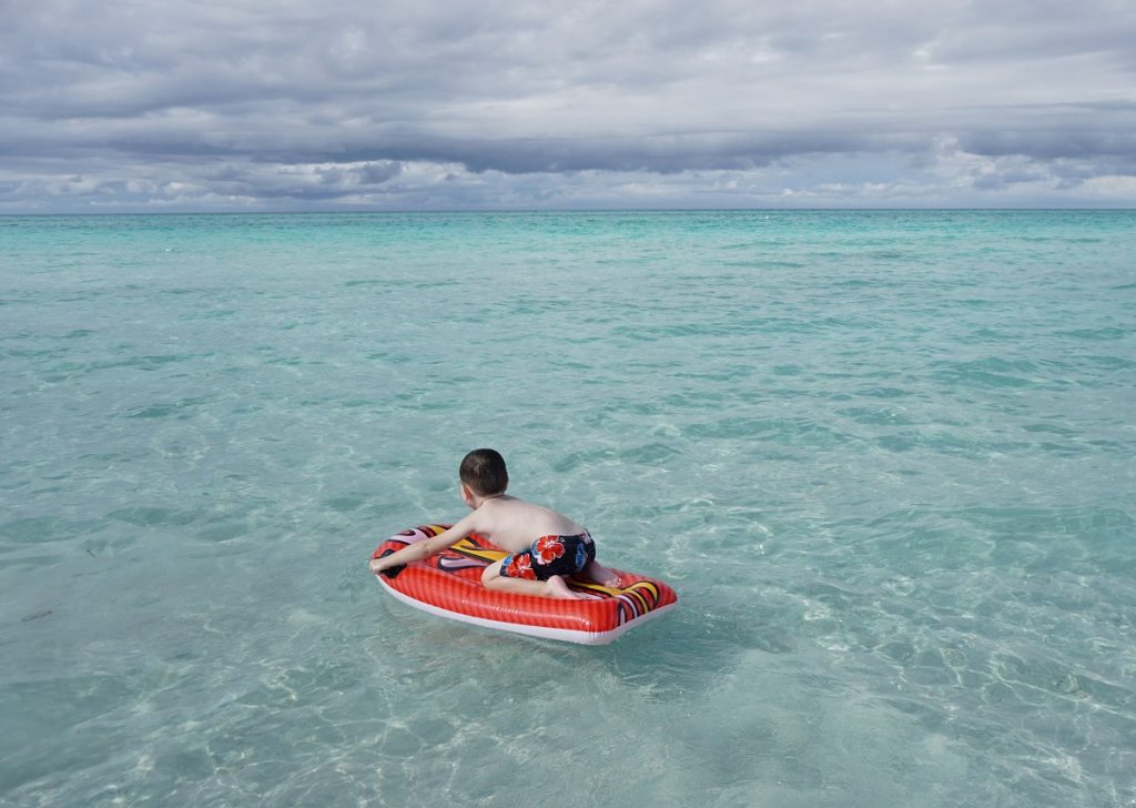 child floating on waves - learning to surf. Cuba with a baby planning.
