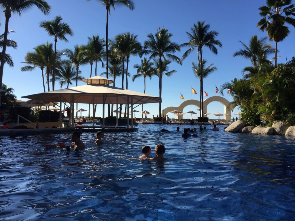 a photo of a resort swimming pool with people silouettes