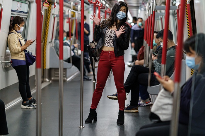 asian lady wearing a face mask and not touching anything on a train she travels