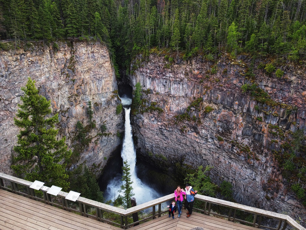 family posing for a photo in front of Spahats Falls in Wells Gray Park - aerial view from a drone