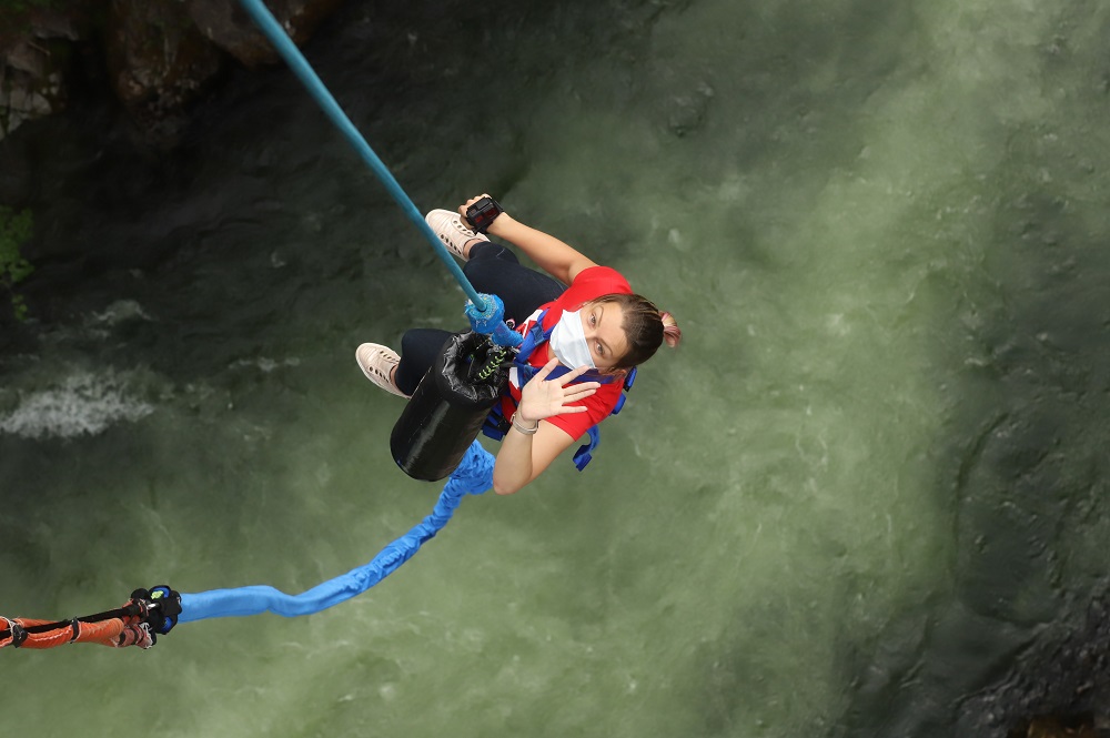 woman in red tshirt is being pulled up after a bungee jump