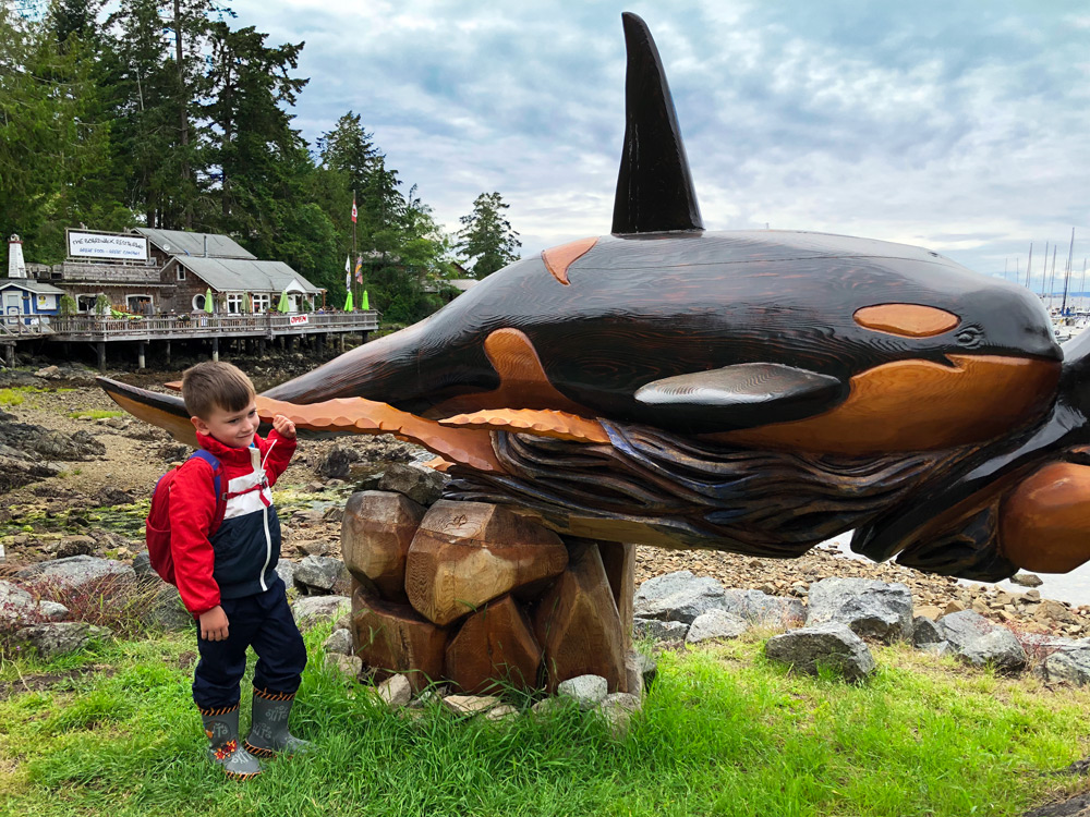 a child next to a carved orca in Lund BC