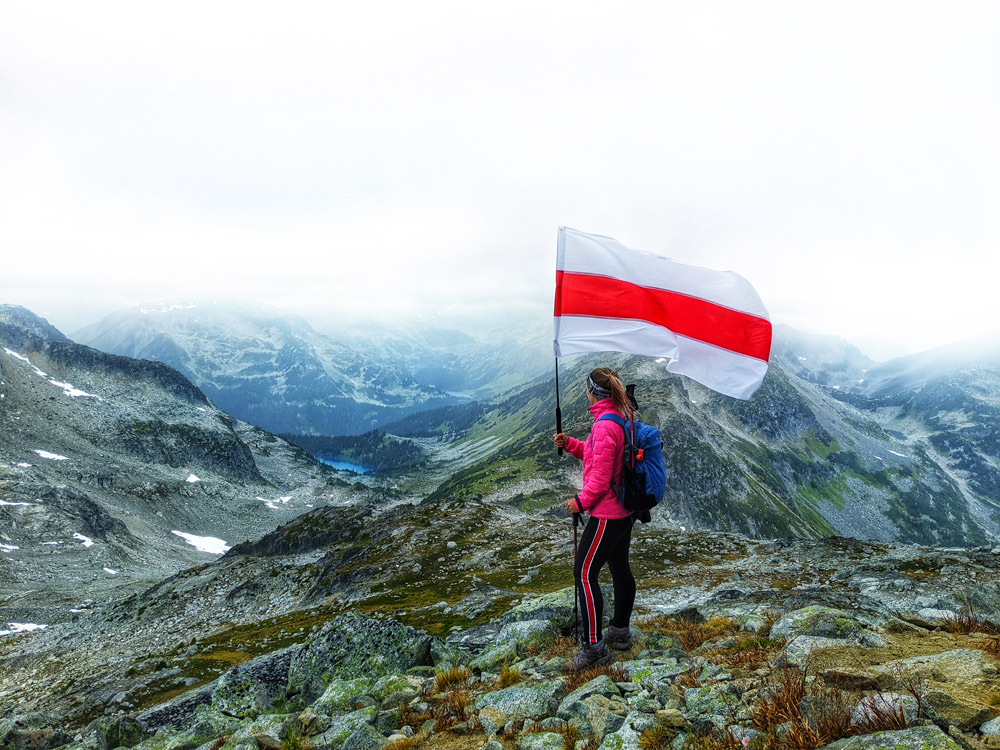Mt Rohr BC Canada summit peak - girl with Belarus flag over mountain range