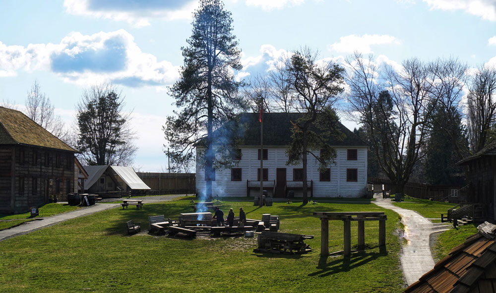 Historic Fort Langley Site - white house and main lawn with people around the fireplace