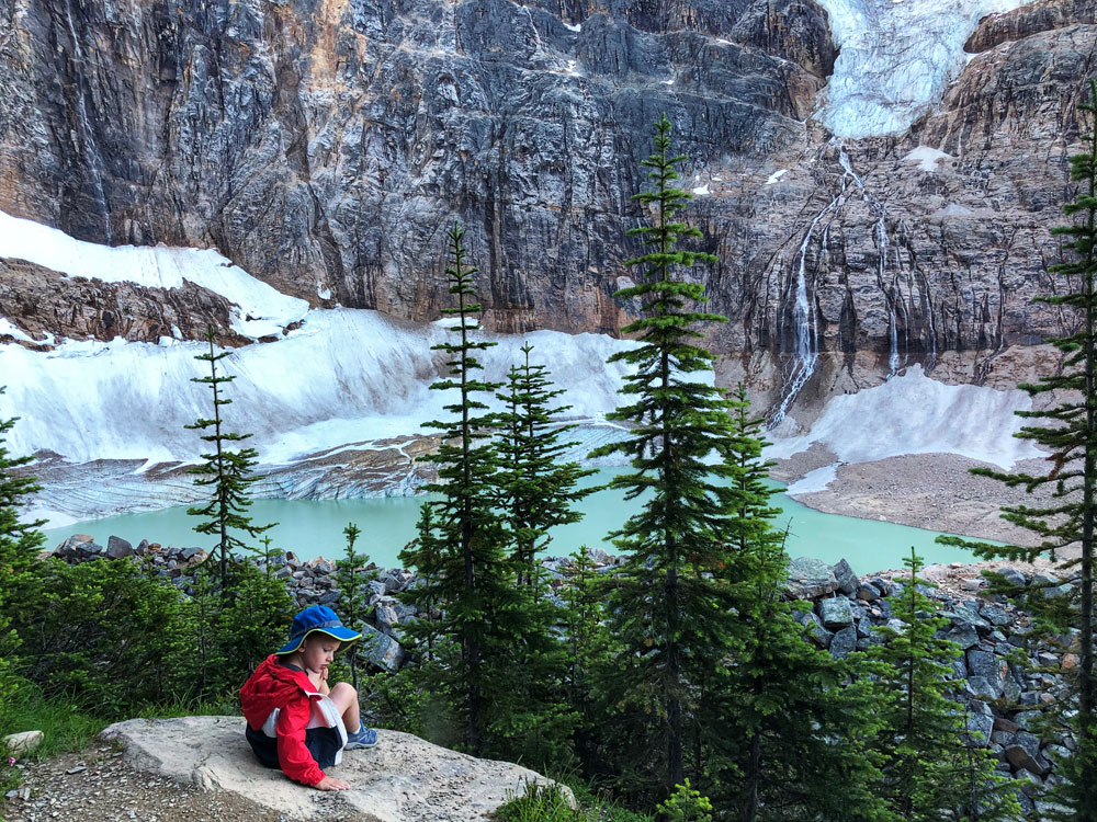 a child in red jacket looking at a glacier lake horizontal