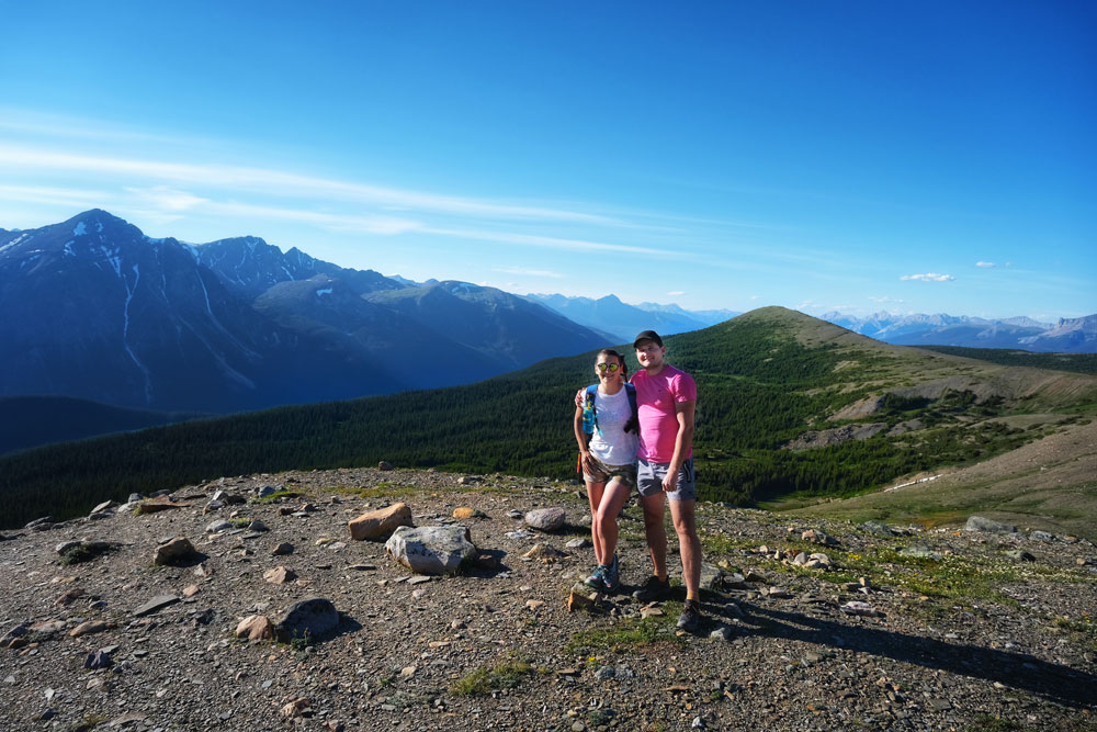 a couple posing for photos with a backdrop of Canadian Rockies