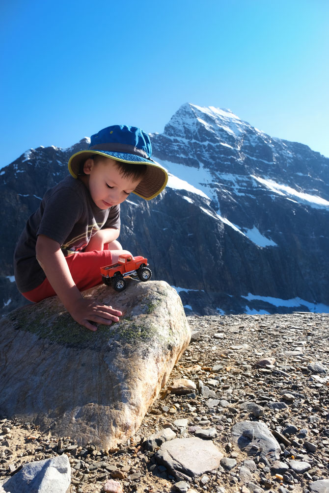 a child playing with orange truck with Mount Edith Cavell as his backdrop