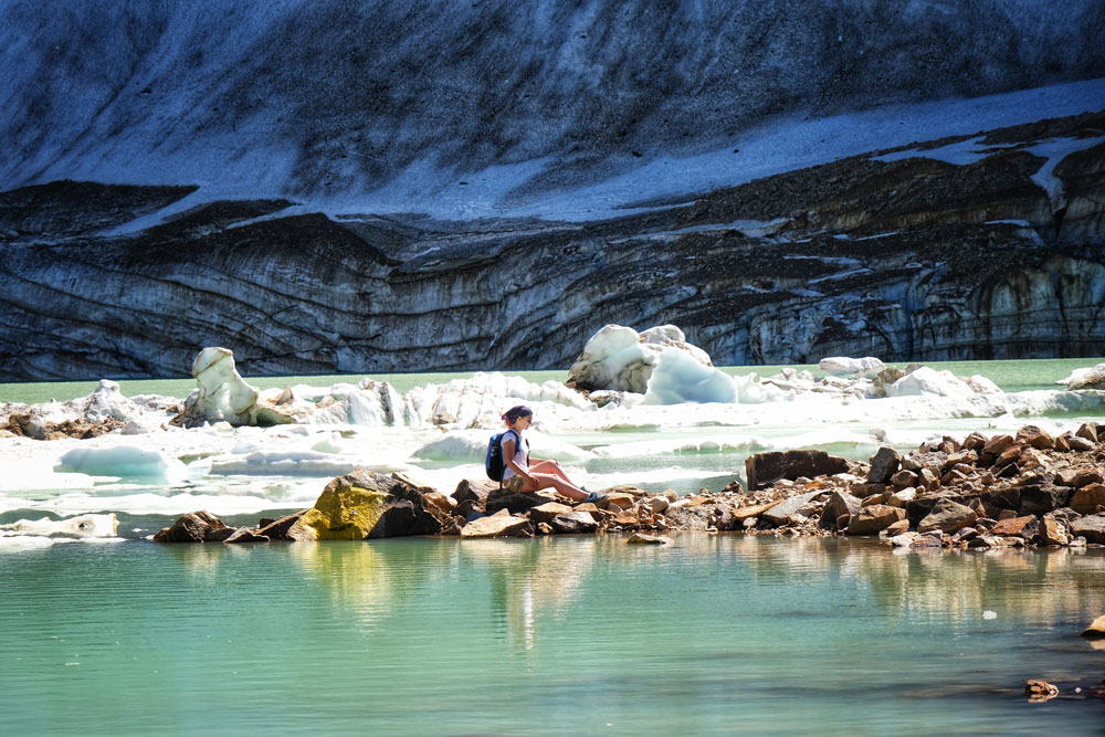 surreal view of the Angel Glacier lake with a woman hiker resting on the ice