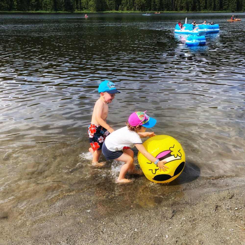 two children playing with a yellow inflatable ball at the Rolley Lake near Maple Ridge BC
