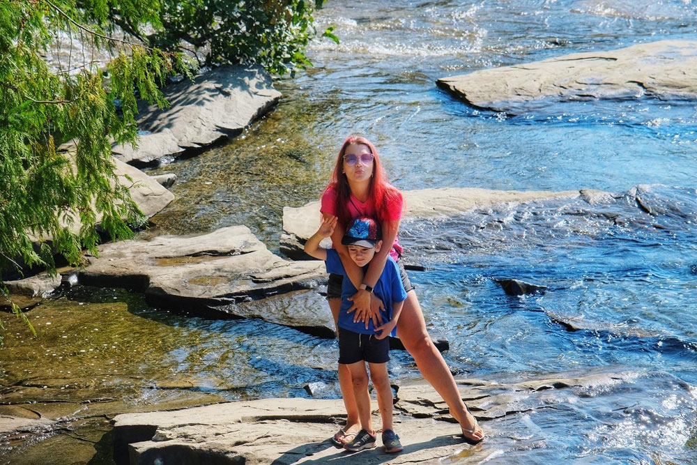mother and son posing for photography at a waterfall