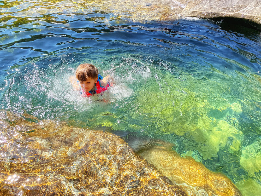 child swimming in a waterfall on a summer day