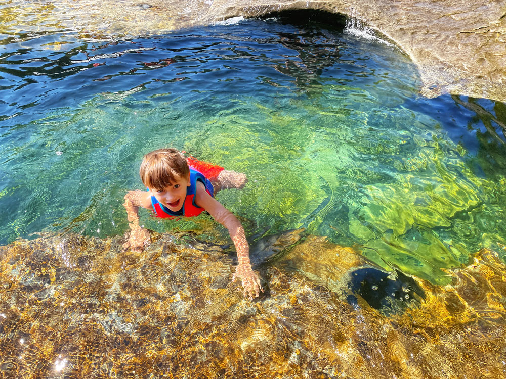 child swimming in a waterfall on a summer day at Nymph Falls Nature Park