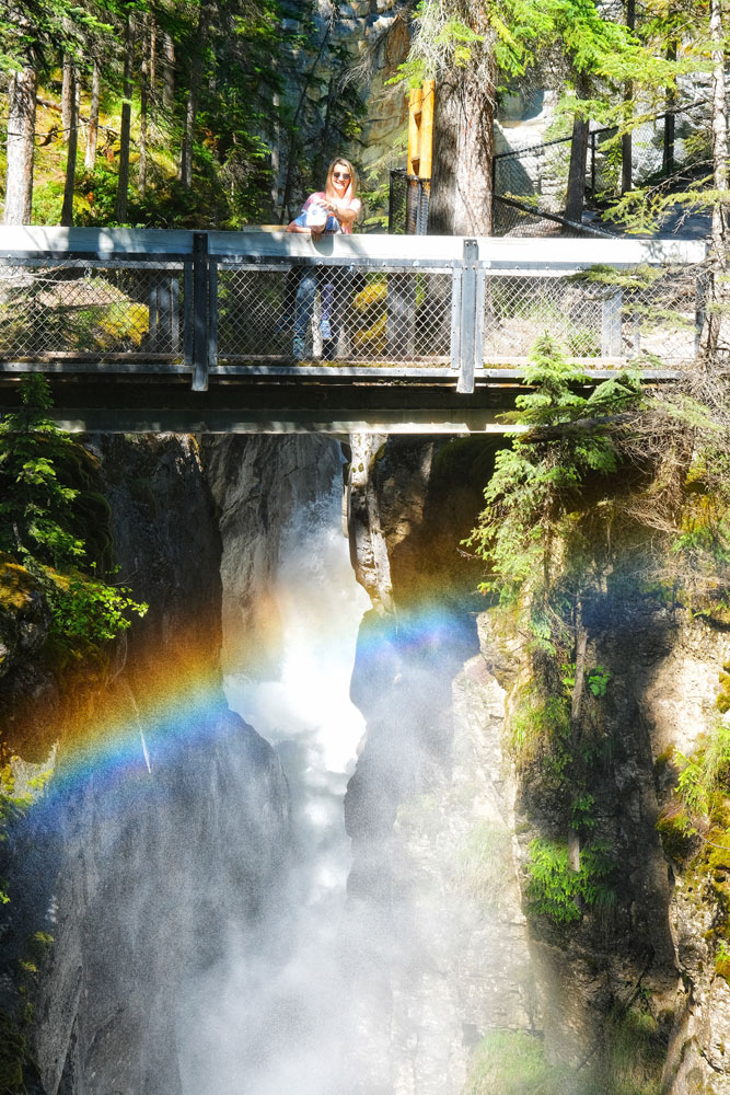 Maligne Canyon hike - waterfalls creating multiple rainbows as tourists are standing on a bridge