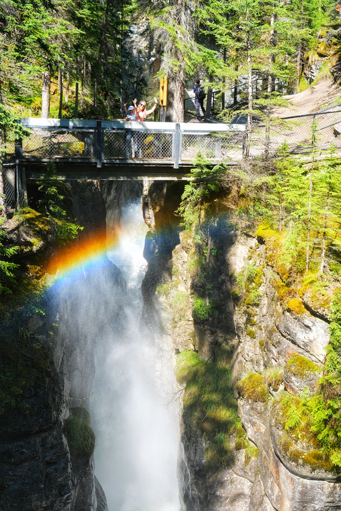 Maligne Canyon Jasper AB hike - waterfalls creating rainbows as tourists are standing on a bridge