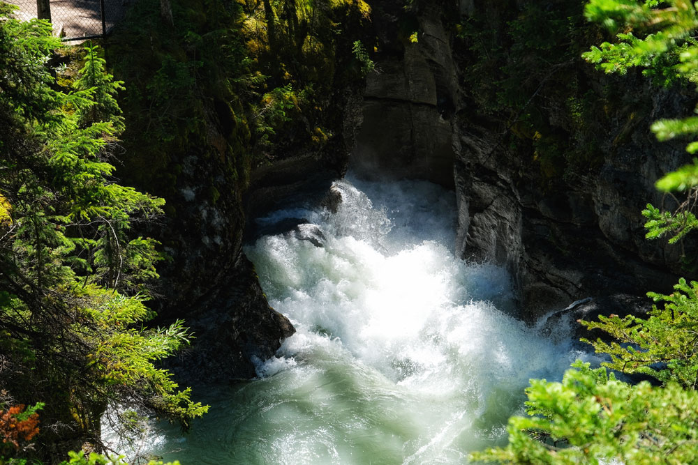 Summer hiking Maligne Canyon rushing waters view from a bridge